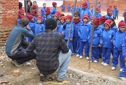 Building Local children in Nepal look on excitedly while volunteers help with building classrooms for a school damaged during the 2015 earthquake.