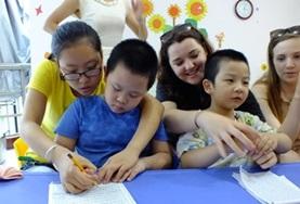 Care Childcare volunteers work closely with children from a kindergarten in China, helping them to draw and colour in.