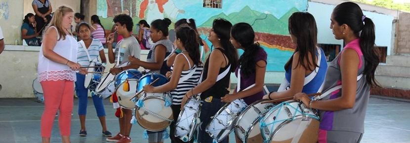 Teenagers take part in drum lesson at Music Project Projects Abroad volunteer teaches a group of children drums at the Music Project in Ecuador