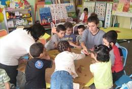 Care A high school student volunteering in Morocco runs an educational activity with children, under the guidance of a local teacher.