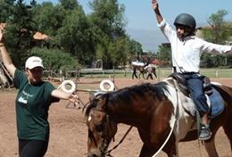 Care A high school volunteer assists a local child with riding his therapy horse on our Equine Therapy & Community project in Bolivia.