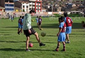 Sports A Sports volunteer teaches school children his technique for kicking a soccer on our Multi-sports project in Peru.