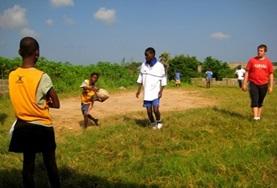 Rugby A Sports volunteer works with school children on passing a rugby ball at one of our Rugby placements.