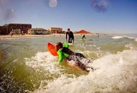 Surfing A volunteer works with disadvantaged children, teaching them to surf and promoting exercise.