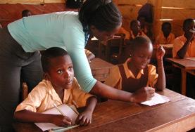 Ghana A Teaching volunteer works with a school student in Ghana, helping her to complete an English language exercise during class.