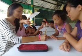 Philippines A Teaching volunteer works closely with school students during an English language lesson at our placement in the Philippines.